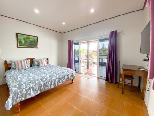 a bedroom with a bed and a desk and a window at Bansuwan Homestay in Amphawa