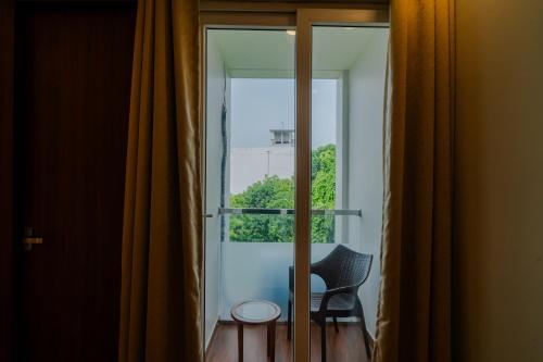 a room with a glass door with a chair and a window at Alokah Kashi in Varanasi