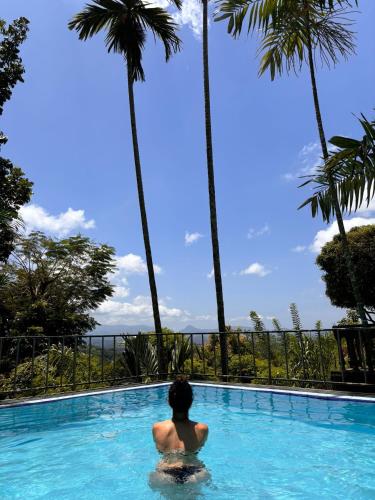 a man sitting in a swimming pool with palm trees at Range Kandy in Kandy