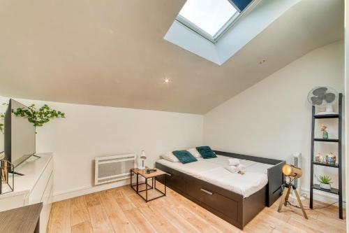 Un dormitorio con una cama y una claraboya. en Le Nid Blanc - Agréable studio tout équipé, en Oullins