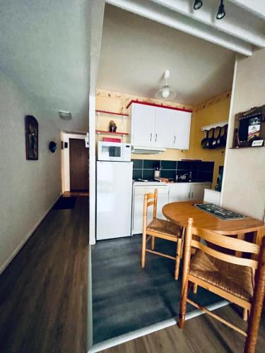 une cuisine avec une table et un réfrigérateur blanc dans l'établissement Appartement au pied des pistes - Parking gratuit, à Les Deux Alpes