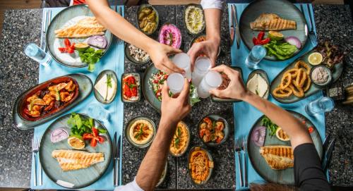 a group of people sitting around a table with food at Acapulco Resort Hotel in Kérynia