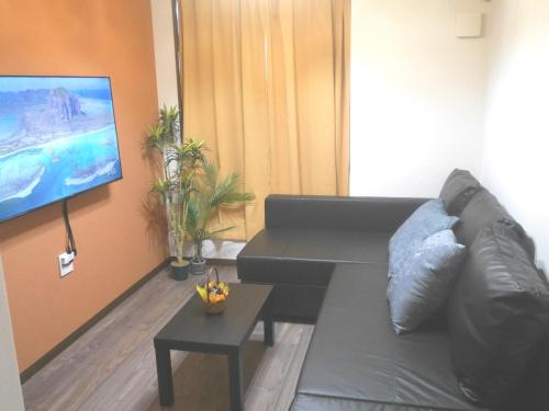 a living room with a couch and a flat screen tv at GuestHouse Grande今宮駅前 in Osaka