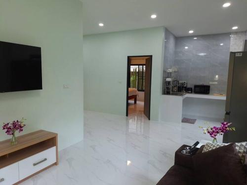 a living room with a couch and a tv on a wall at Baan Si in Haad Tian