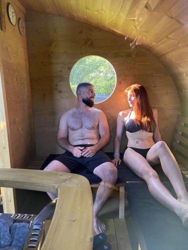 a man and a woman sitting in a swimming pool at La Milardière Chambres d'Hôtes in Theux