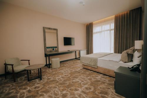 a hotel room with a bed and a desk and a mirror at Hill Park Gusar in Qusar