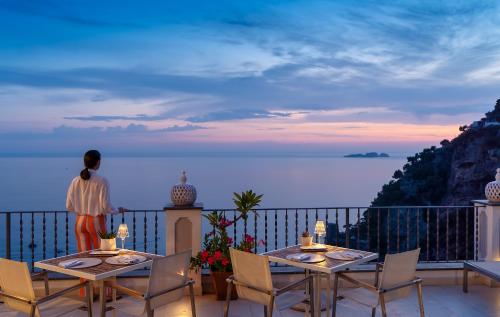 a woman standing on a balcony looking out at the ocean at Hotel Punta Regina in Positano