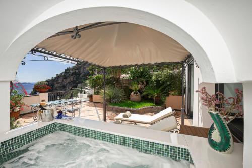 an outdoor swimming pool with an umbrella and a tub at Hotel Punta Regina in Positano