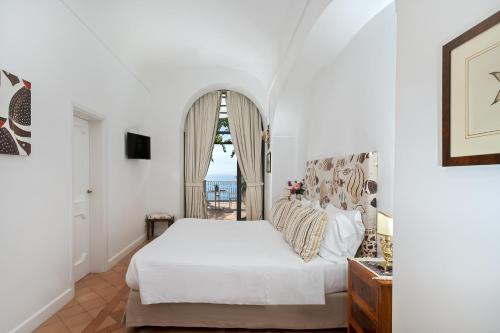 a bedroom with a white bed and a window at Hotel Punta Regina in Positano