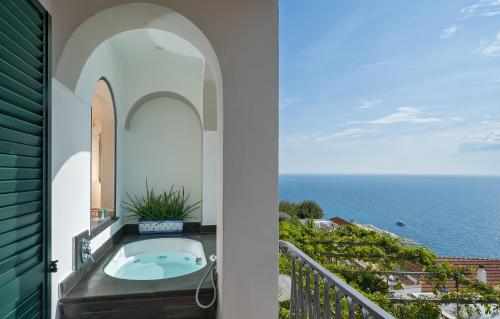 a bathroom with a tub on a balcony with the ocean at Hotel Punta Regina in Positano