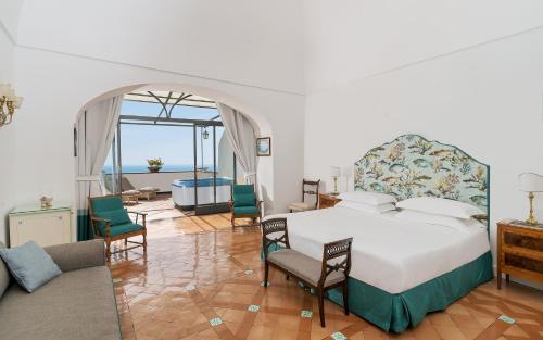 a bedroom with a bed and a living room with a tub at Hotel Punta Regina in Positano