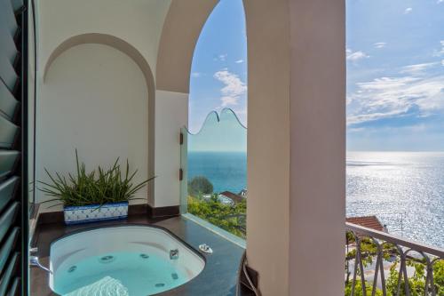 a bath tub in a room with a view of the ocean at Hotel Punta Regina in Positano