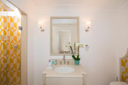 a white bathroom with a sink and a mirror at Hotel Punta Regina in Positano