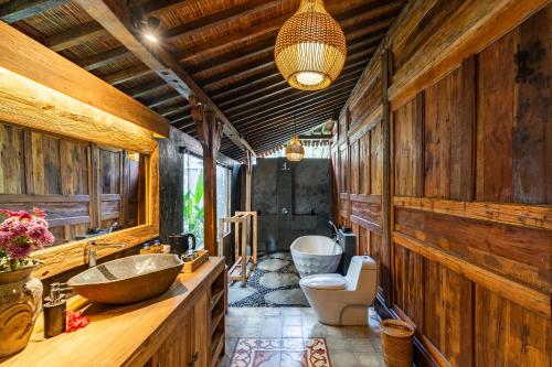 a bathroom with wooden walls and two sinks and two toilets at Madani Antique Villas in Ubud