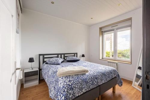 une chambre avec un lit avec une couette bleue et blanche dans l'établissement Maison tout confort 10 personnes - La Halte Bigoudene, à Gourinet