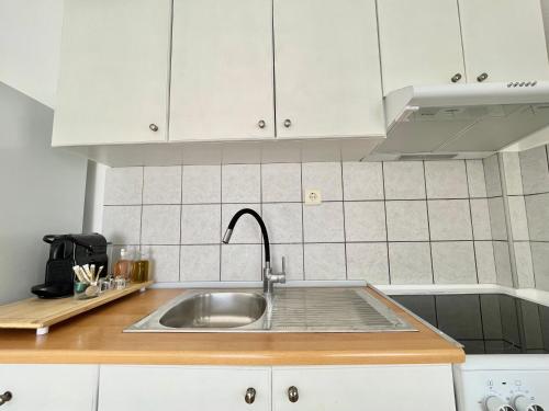 eine Küche mit Spüle und weißen Schränken in der Unterkunft Olea in the city in Gázion