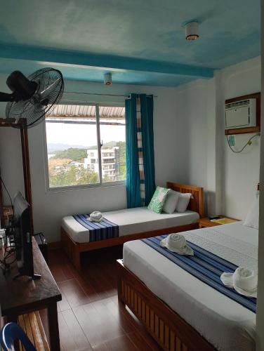 a bedroom with two beds and a window with a fan at Casa Montemar Bed and Breakfast in Coron