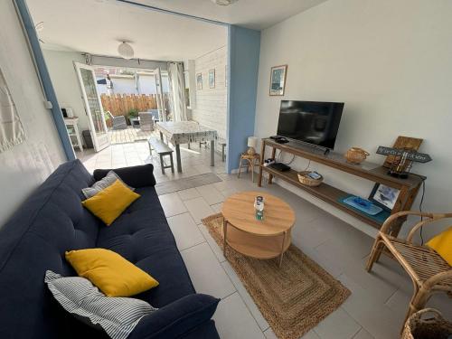 ein Wohnzimmer mit einem blauen Sofa und einem Tisch in der Unterkunft C'est une maison bleue, juste à côté de la plage... in Barneville-Carteret