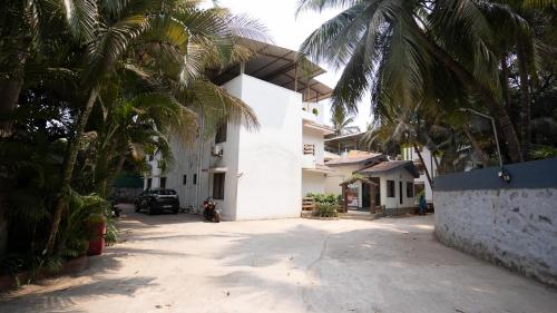 a white house with palm trees in front of it at Ruturaj Inn Alibag in Alibaug
