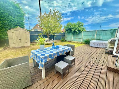 a blue and white table and chairs on a deck at Three Bed Detached Home - Large Garden - Hot Tub - Free Parking - Close to Beach! in Iford