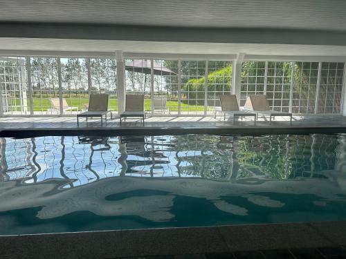 a swimming pool with chairs in a house at Kapelhoeve in De Haan