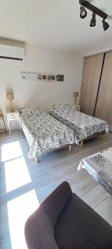 Cette chambre comprend deux lits, une chaise et un canapé. dans l'établissement Studio Lou Cigaloun climatisé, à Gréoux-les-Bains