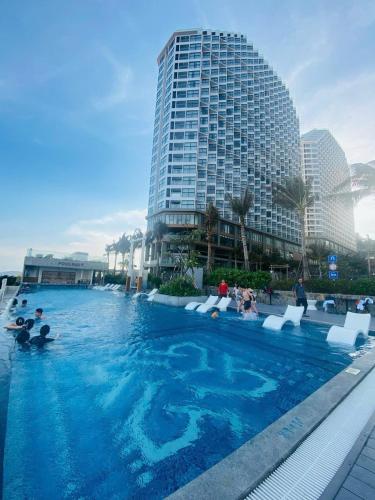 people in a swimming pool with a tall building at APEC Mandala Mũi Né in Mui Ne