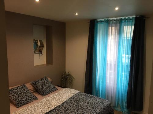 une chambre avec un lit et une fenêtre avec des rideaux bleus dans l'établissement Au bon séjour....., à La Souterraine