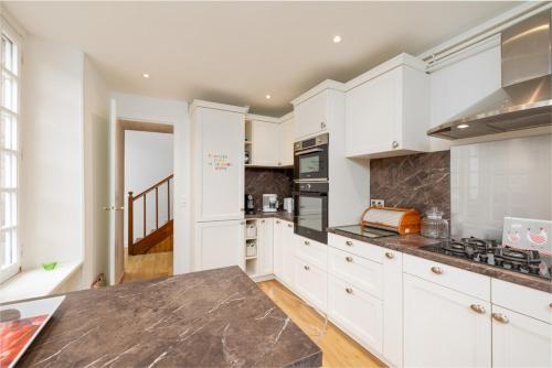 a kitchen with white cabinets and a counter top at Splendide maison de maître à 50m du port et 100m de la plage in Barfleur