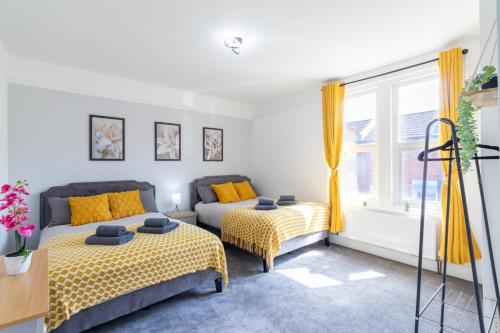 two beds in a room with yellow curtains at Open Mind Property - Cosy Home - 7 Beds & Parking in Portsmouth