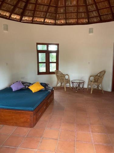 a bedroom with a bed and two chairs and a table at Banyan Beach Cottage SRI LANKA in Kalapu