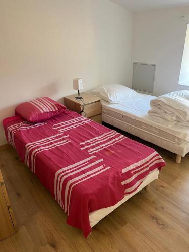- une chambre avec 2 lits dotés de draps rouges et blancs dans l'établissement Appartement 5 chambres dans le centre du village, à Pélussin