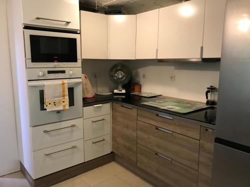 une cuisine avec des armoires blanches et un four à plaques de cuisson dans l'établissement Charmant studio avec jardin, à Cannes