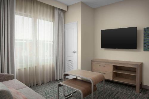 a living room with a tv and a couch and a table at Homewood Suites by Hilton Irving-DFW Airport in Irving
