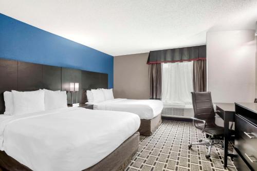 a hotel room with two beds and a desk at Comfort Suites Nashville Airport - BNA in Nashville