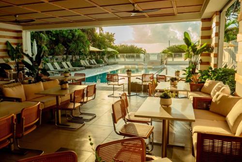 a restaurant with tables and chairs and a swimming pool at MB Hotel, Trademark Collection by Wyndham in Miami Beach