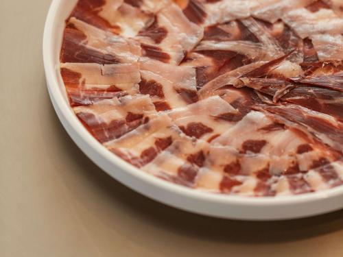a bowl of food with bacon on top of it at Mondrian Ibiza in Cala Llonga