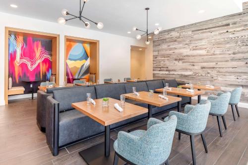 a restaurant with wooden tables and blue chairs at Cambria Hotel Denver Downtown RiNo in Denver