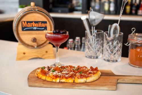 a pizza on a wooden cutting board with a drink at Cambria Hotel Denver Downtown RiNo in Denver