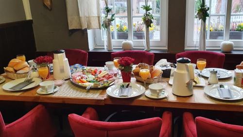 a table with food on it with red chairs at Hotel SchlossStuben in Nordkirchen