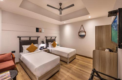 two beds in a room with a tv and a couch at Comfort Inn Grand, Kaushambi in Ghaziabad