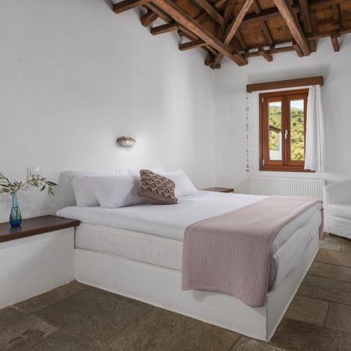 a white bedroom with a white bed and a window at Aeolos Hotel & Villas - Pelion in Chorefto