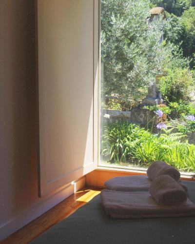 a room with a large window with towels on a bed at Gerês - Casa da Cabana in Vieira do Minho
