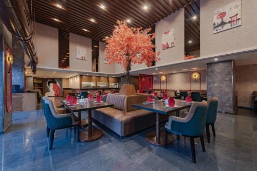 a restaurant with tables and chairs and a tree at Goldfinch Hotel Mangalore in Mangalore