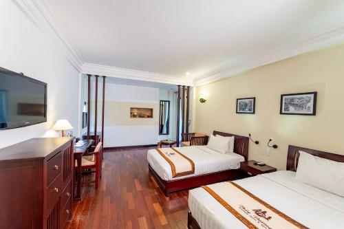 a hotel room with two beds and a desk and a tv at ANNAM HERITAGE - Thuy Duong 3 in Hoi An