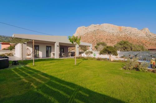 a house with a green yard with a mountain in the background at Blue Lagoon Villa in Stavros