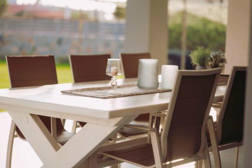 a white table with chairs and a glass of wine at Blue Lagoon Villa in Stavros