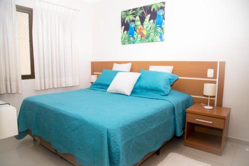 a bedroom with a bed with a blue comforter at Flat Golden Beach Pitangueiras com Vista Mar in Guarujá