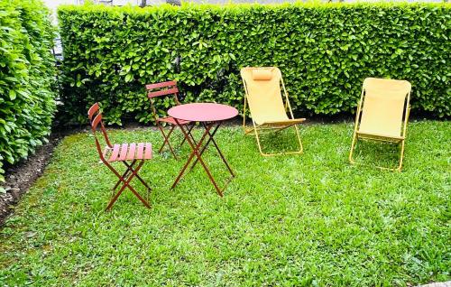 three chairs and a table in the grass at Appartement standing avec jardin, 4 personnes, stratégiquement situé in Mantes-la-Jolie
