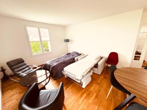 a living room with a bed and a table and chairs at Appartement standing avec jardin, 4 personnes, stratégiquement situé in Mantes-la-Jolie